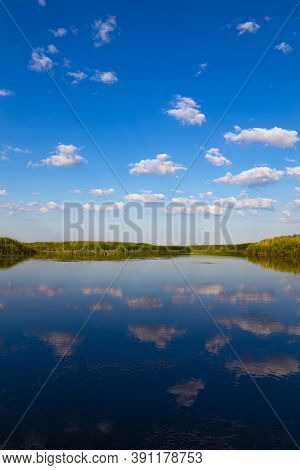 Scenic View Over The Lake. White Clouds On Blue Sky Are Mirrored  Reflected In The Water Surface. Na