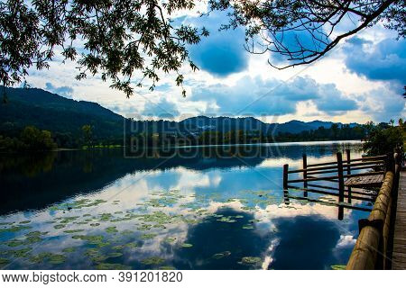 Blue Clouds Are Reflected On The Lake With Wooden Jetty On The Lakes Of Revine, Treviso, Veneto, Ita