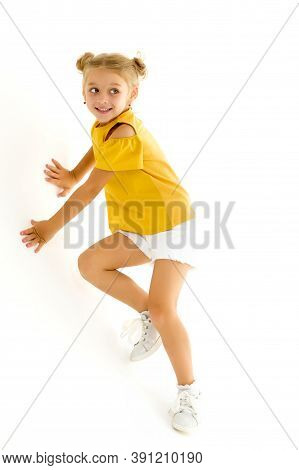 A Cute Little Girl Leaned Against A White Wall. Cyclorama In Studio. Isolated On A White Background.