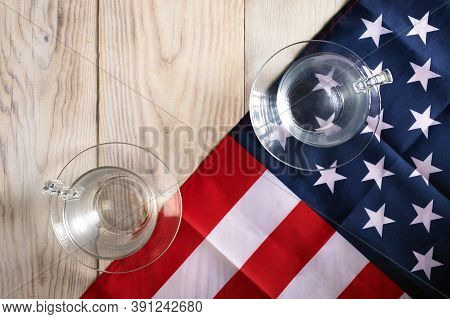 Concept Of Single Candidate Winning An American Election. One Glass On American Flag, Other On Table