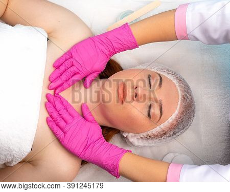 Close-up Of A Young Woman Receiving A Cosmetic Facial Massage In A Beauty Salon And The Hands Of The