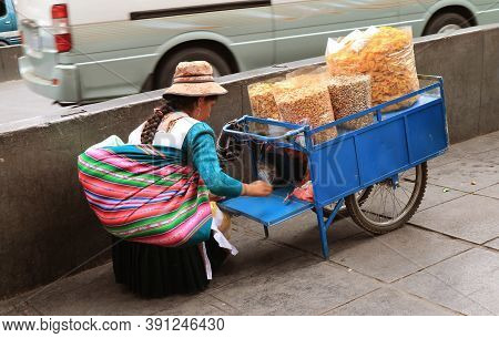 Street Vendor With Her Cart Filled With Delectable Snacks, The Sidewalk In Downtown La Paz, Bolivia,