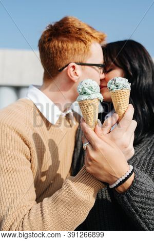 Immersed Couple Sitting Outdoors, Holding Ice Cream, Sensually Kissing