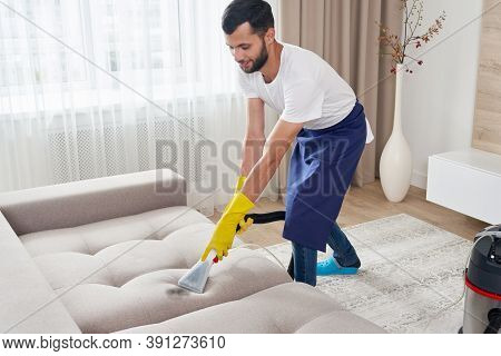 Close-up Of Housekeeper Holding Modern Washing Vacuum Cleaner And Cleaning Dirty Sofa With Professio