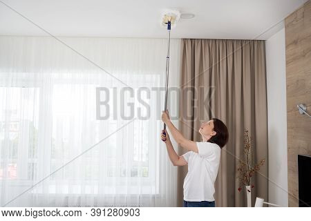 Woman Cleaning Ceiling With A Mop. Housewife Cleaning Living Room