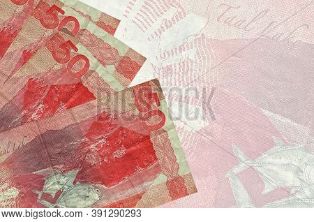 50 Philippine Piso Bills Lies In Stack On Background Of Big Semi-transparent Banknote. Abstract Busi