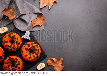 Pumpkin And Chocolate Donuts, Spooky Ghosts Marshmallows And Dried Leaves On Grey Stone Table Top - 