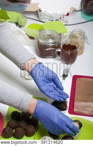A Woman In Rubber Gloves Makes Candies From Dried Fruits And Nuts. Some Are Sprinkled With Sesame Se