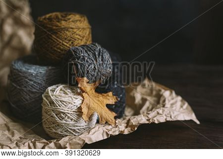 Cozy Balls Of Yarn For Hand Knitting With Dry Oak Leaf On A Dark Background. Autumn Background For H