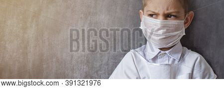 A Serious, Focused Boy In A Medical Mask And A White Coat, Stands Against The Background Of A Black 