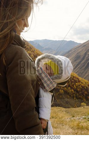 Portrait Of Young Beautiful Woman With Her Little Sleeping Daughter In Ergo Carrier On A Background 