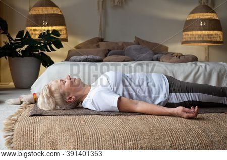 Senior Caucasian Woman Lying On Yoga Mat After Workout