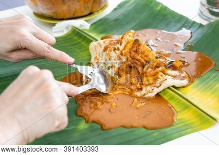Person Eating Roti Canai Or Paratha Served With Curry Served On Banana Leaf