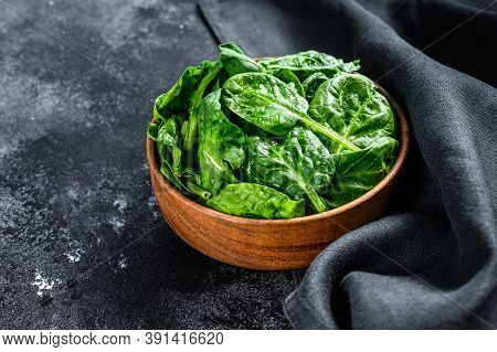 Fresh Spinach Leaves In A Wooden Bowl. Black Background. Top View