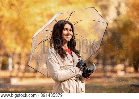 Change Of Season Concept. Dreamy Millennial Woman Using Umbrella During Her Walk At Park On Rainy Au