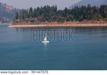 Lost Creek Lake Near Prospect,  Oregon / Usa - September 7, 2014:  A Small White Sailboat Skims The 