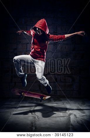 Skateboardista dělá trik s grunge pozadí červená mikina a dovednost