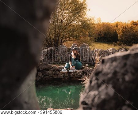 Wide Portrait Of An Attractive Brunette Sitting On A Well At The Rajcica Wells Natural Landmark. Gir