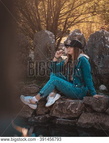 Portrait Of An Attractive Brunette Sitting In A Stone Well At The Rajcica Wells Landmark. Wearing Je