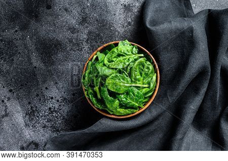 Fresh Spinach Leaves In A Wooden Bowl. Black Background. Top View