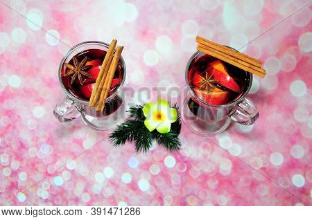 Two Glasses Of Red Hot Wine With Cinnamon Sticks And Anise On A Pink Background And A Branch Of A Co