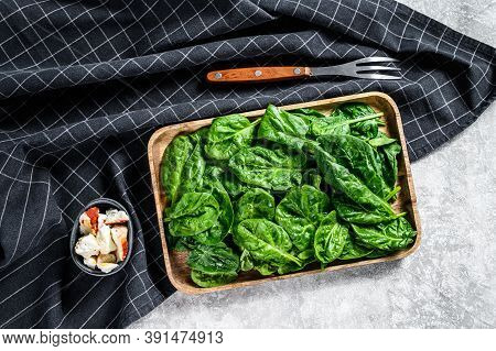 Young Spinach Leaves In A Wooden Bowl With Goat Cheese. Gray Background. Top View