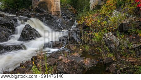 Running water of Dead river through rocky terrain in Michigan Upper Peninsula with colorful fall foliage