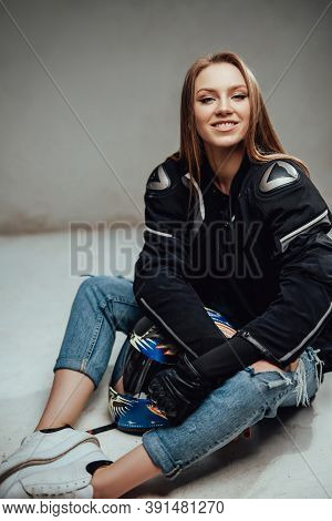 Cheerful And Cute Female Motorcyclist Poses Sitting On Floor With Her Helmet And Looking At Camear I