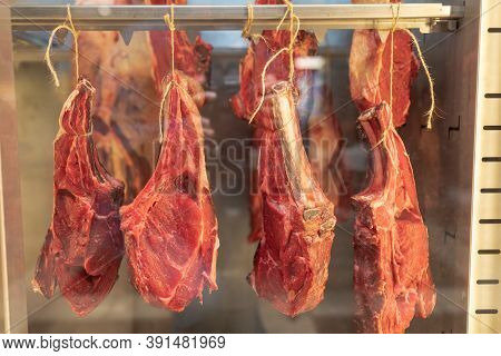 Fresh Raw Meat On The Bone Hanging From A Rope In A Shop Window