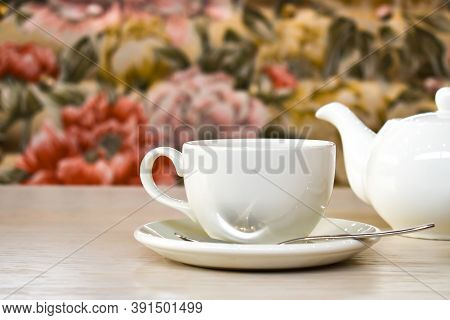 White cup and teapot on the background of a cozy interior in the restaurant. A couple of tea on the