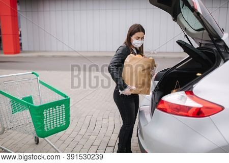 Groceries In Females Hand By The Car Truck. Woman In Protective Mask And Disposable Gloves. Fresh Fr