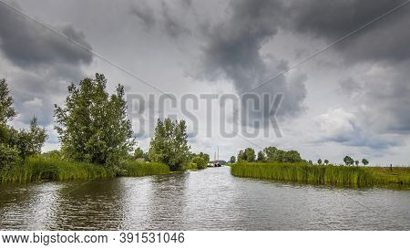 View In Canal And Lake Shore With Reeds And Typha Under Cloudy Summer Sky