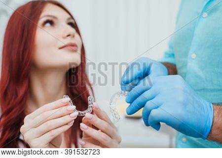 Doctor Orthodontist Shows A Woman Silicone Aligners To Straighten Teeth