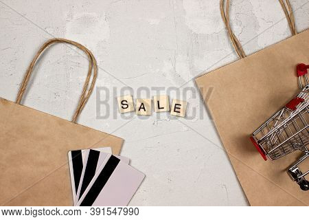 Sale Word Made Of Wooden Blocks, Shopping Bags And Cart, Credit Cards Flat Lay On Concrete Backgroun