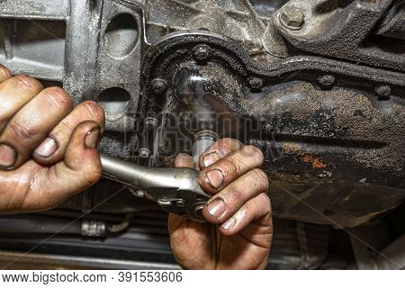 The Car Mechanic Bolts A New Screw With A Copper Washer To The Oil Sump, In A Diesel Engine.