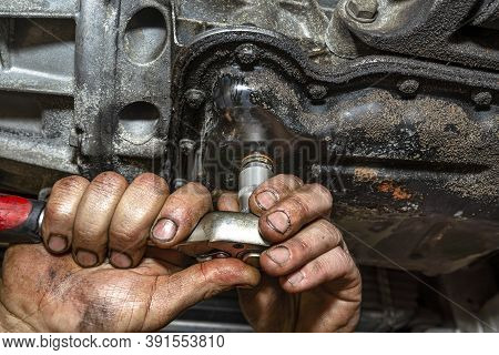 The Car Mechanic Bolts A New Screw With A Copper Washer To The Oil Sump, In A Diesel Engine.