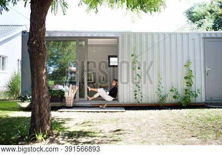 Mature Woman Working In Home Office In Container House In Backyard, Resting.