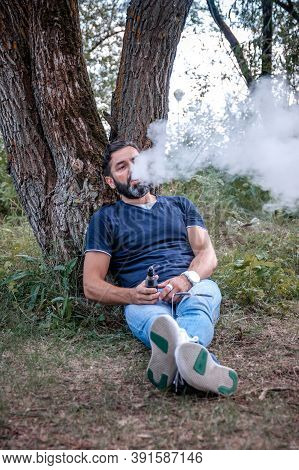 Brutal Smoker Enjoying An Electronic Cigarette On The Ground. Electronic Cigarette As Alternative To