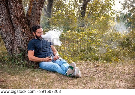 Stylish Brutal Smoker Enjoying An Electronic Cigarette In The Daylight. Hybrid Cigarette.