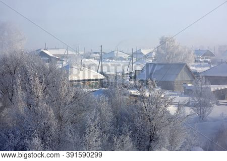 Winter Landscape With A Small Village In Russia. Small Snow-covered Houses, Smoke From Chimneys. Fre