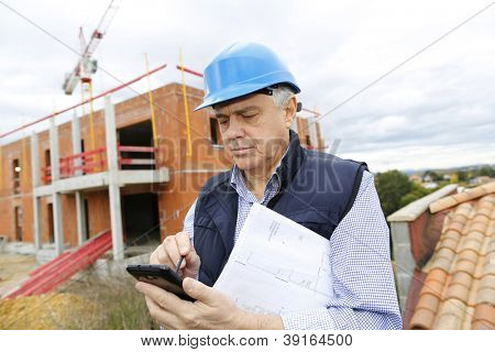 Gerente de construcción en obra con smartphone