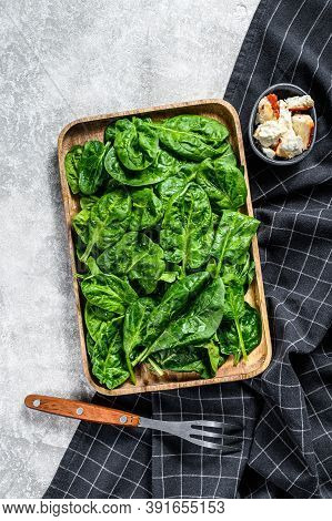 Fresh Spinach Salad In A Wooden Bowl With Goat Cheese. Gray Background. Top View
