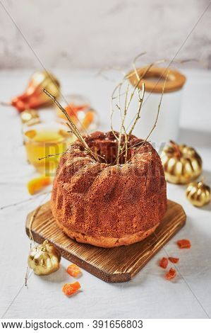 Homemade Autumn Carrot Or Pumpkin Bundt Cake With Candied Fruits, Cup Of Tea And Golden Decorative P