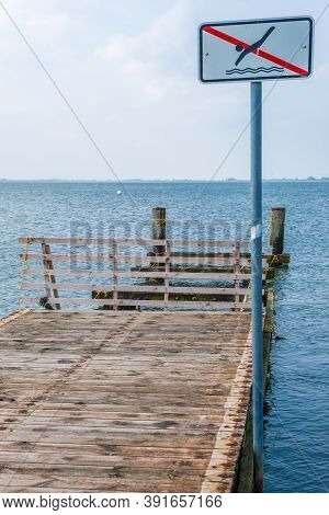 A Wooden Pier On The North Sea Coast With A Sign Bathing Is Prohibited