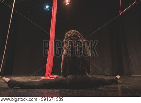 Young woman does aerial acrobatics with red fabrics