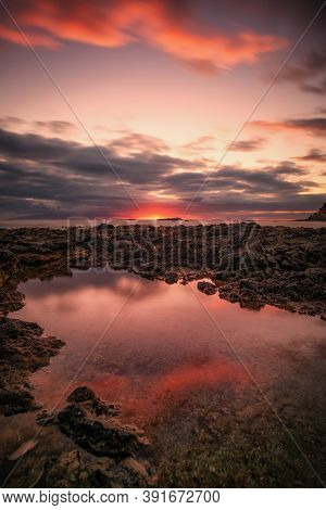 Puddle In The Sea Where The Clouds Are Reflected In A Sunset