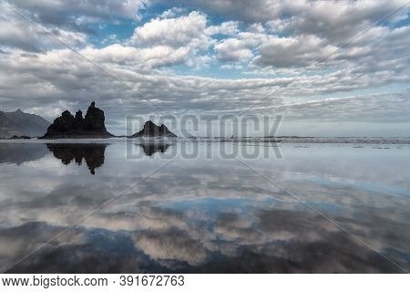 View Of A Beach With Clouds And Sky Reflected In The Water