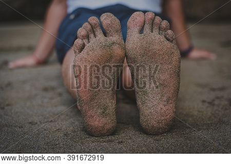 Feet Of An Adult Man Full Of Sand Lying On The Beach And Relaxed