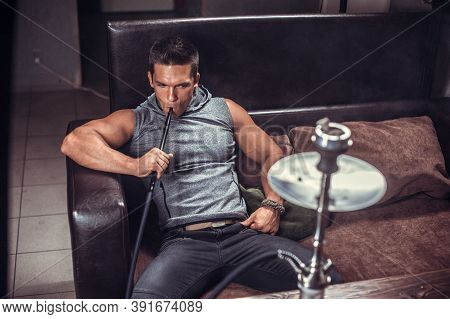 Young Man Relaxes In A Hookah In The Hookah Bar.