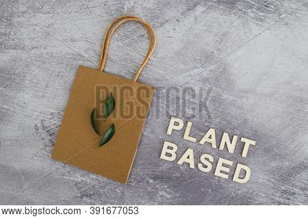 Sustainable Consumer Choices, Plant-based Text With Shopping Bag And Leaves On Concrete Background